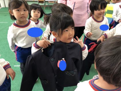 ２歳児は年少組への進級が目前です。今日は３歳児さんと交流をしました。「年少になったら制服になるよ」と教えてもらい、身体に合わせていました。４月が楽しみです。